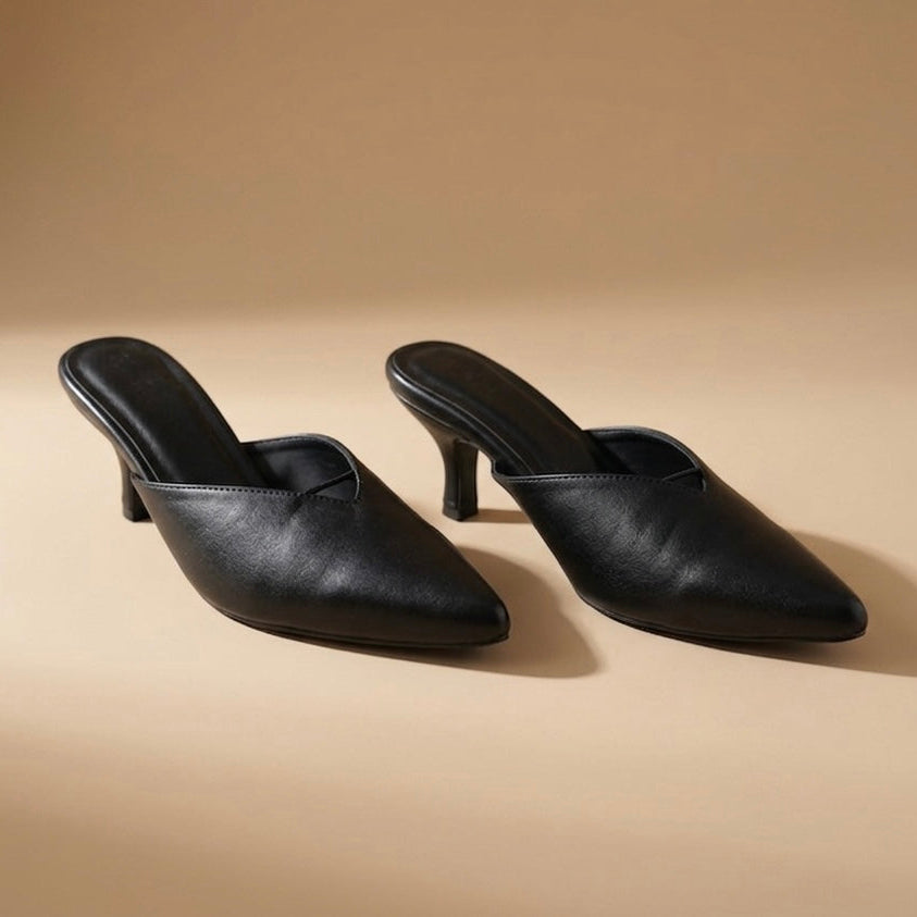 Pair of black high-heeled shoes on a beige background