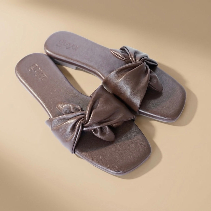 Pair of gray sandals with bow details on a beige background