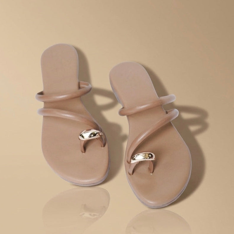 Pair of beige sandals with a decorative strap on a beige background